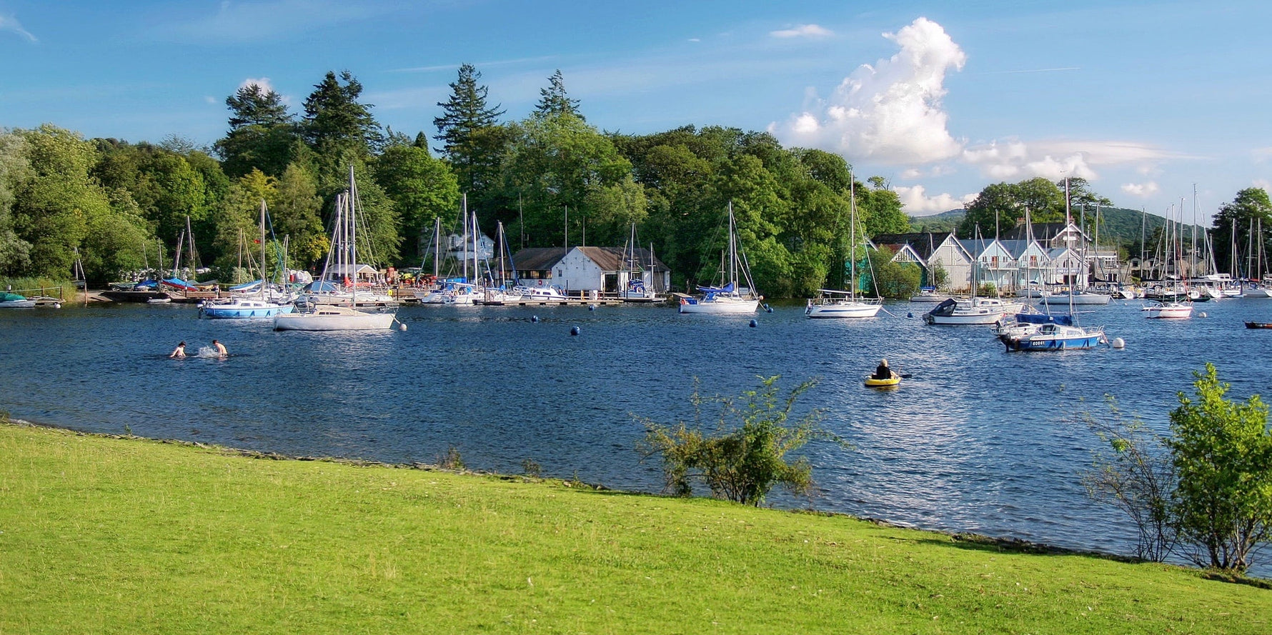 The boats, boat houses, and woods of Bowness Bay in Bowness-on-Windermere on a summer's day. Photo by Jorge Franganillo, licensed CC-BY-3.0