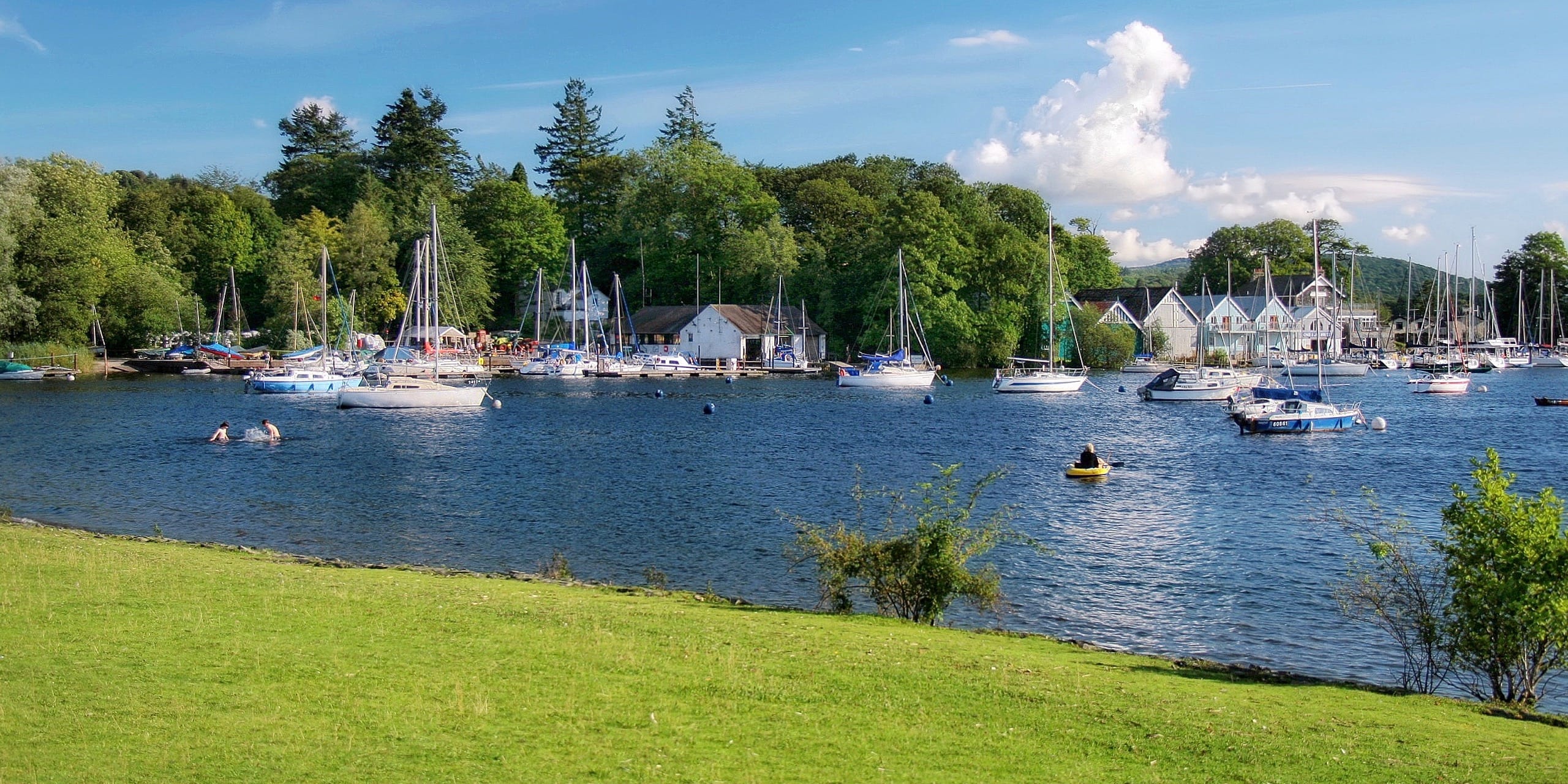 The boats, boat houses, and woods of Bowness Bay in Bowness-on-Windermere on a summer's day. Photo by Jorge Franganillo, licensed CC-BY-3.0